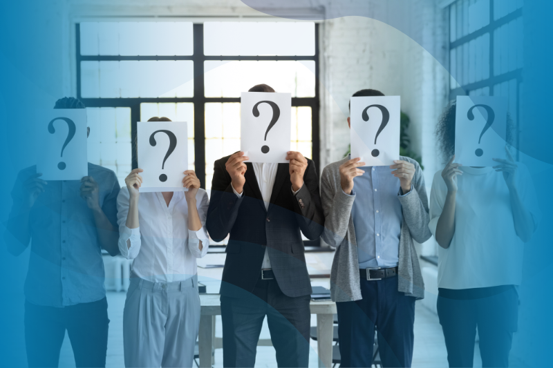 A Group Of People In A Line Holding Papers In Front Of Their Heads With Question Marks On Them