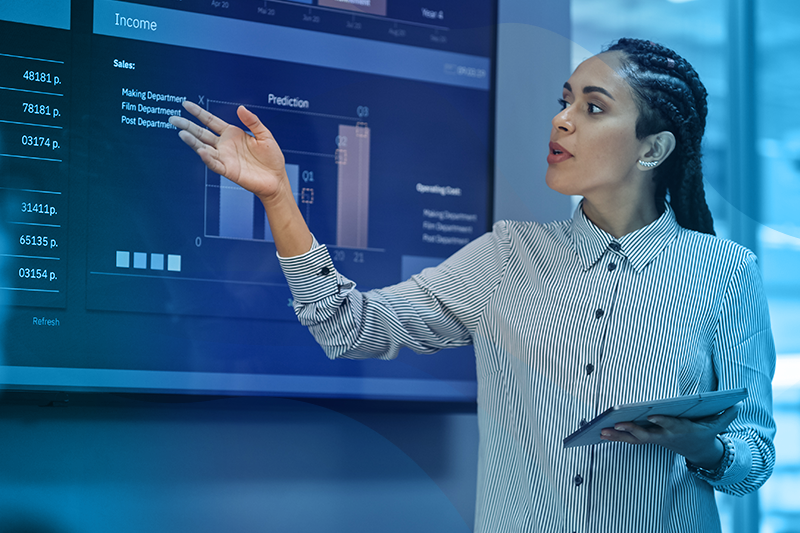 Woman Presenting In Front Of A Screen With Bar Graphs