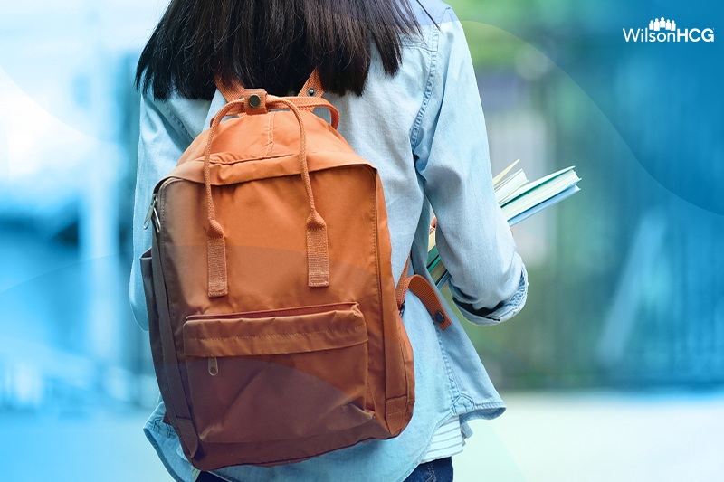 Back view of a woman in a backpack holding books