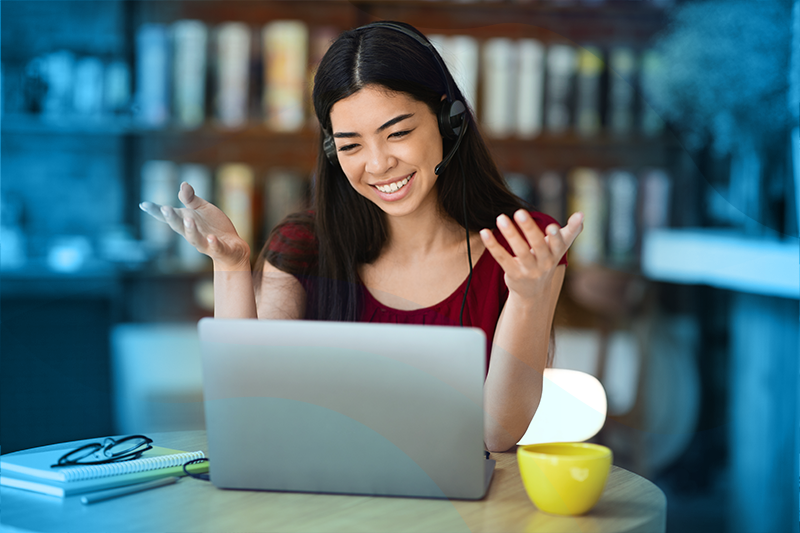 Woman at a laptop smiling with her hands up