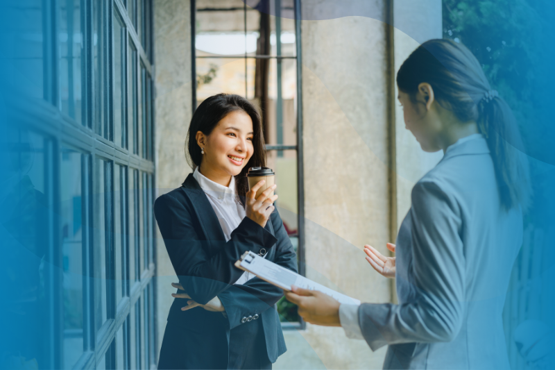 Two young businesswomen standing and talking during lunch break.