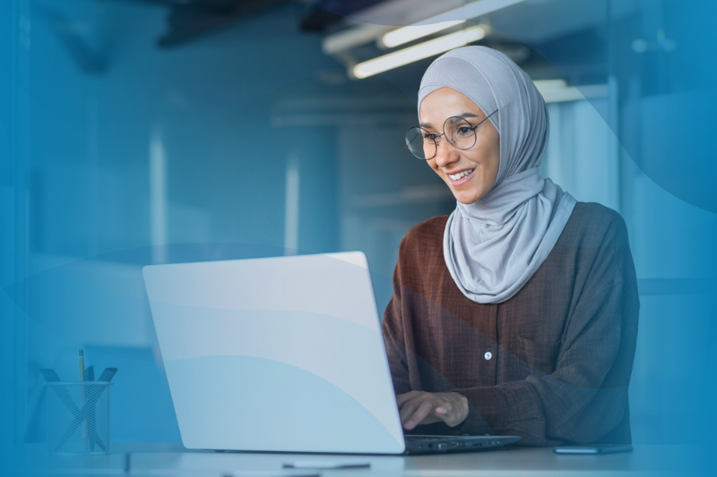 Happy Muslim woman working remotely on laptop