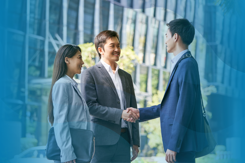 Asian business associates at WilsonHCG shaking hands in downtown area.