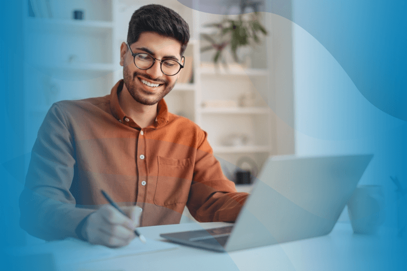 Happy Arabic guy working remotely and taking notes.