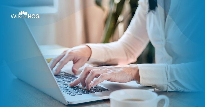 Woman typing on her laptop with a cup of coffee next to her