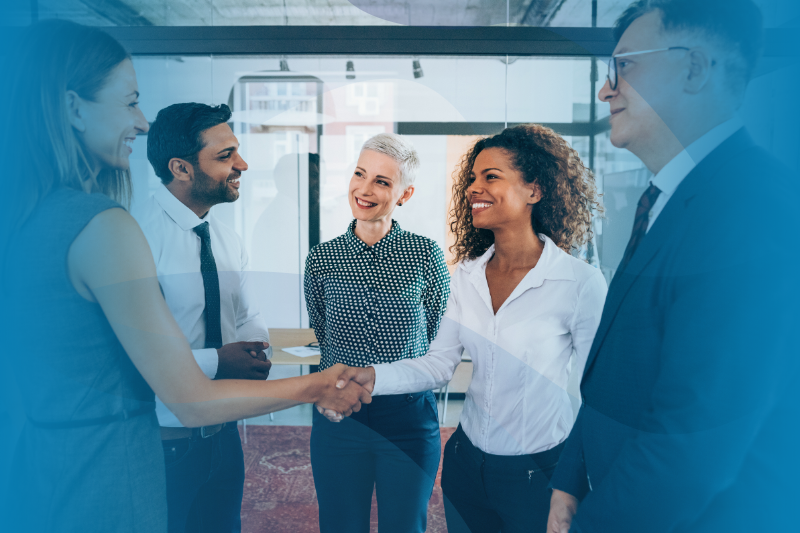 Two women shaking hands over WilsonHCG and iCIMS partnership with a few other men surrounding them