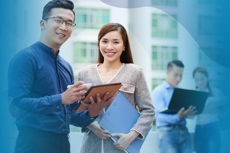 Asian employees smiling with folders and tablet in hand