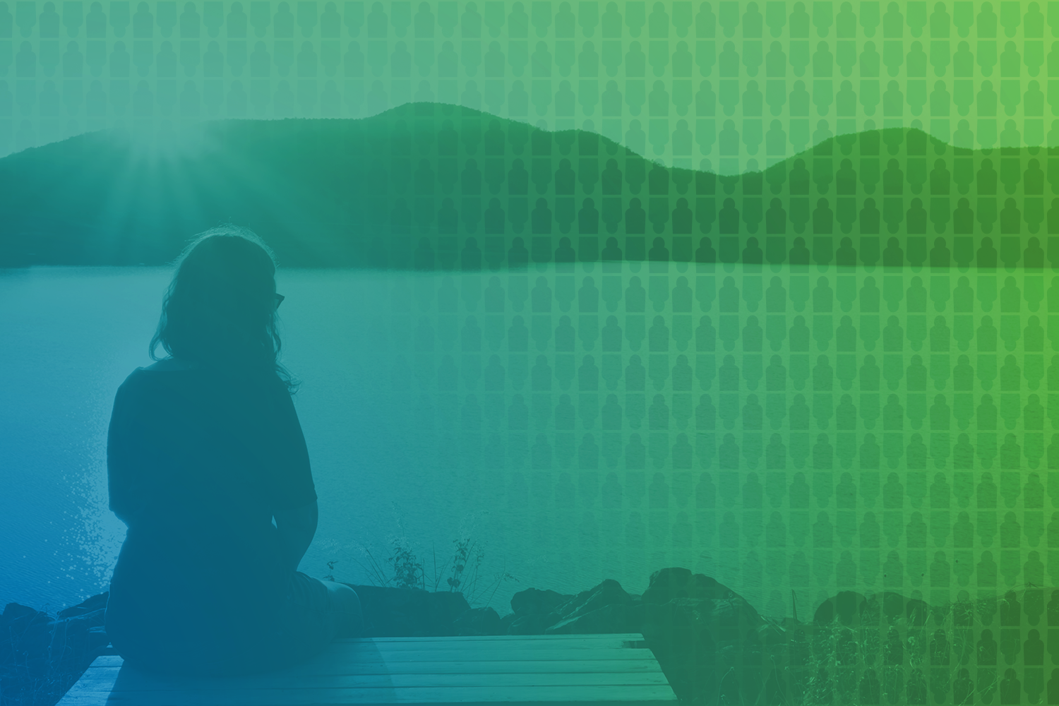 young woman sitting on dock overlooking lake with view of mountains in the background