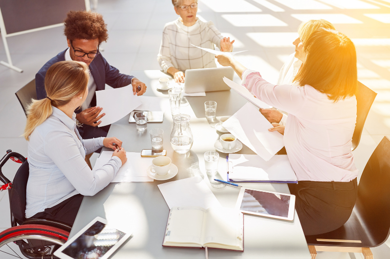 Group of diverse people meeting around a conference room table with papers 