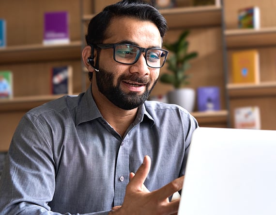 A man wearing glasses reading about direct sourcing and MSP on a laptop