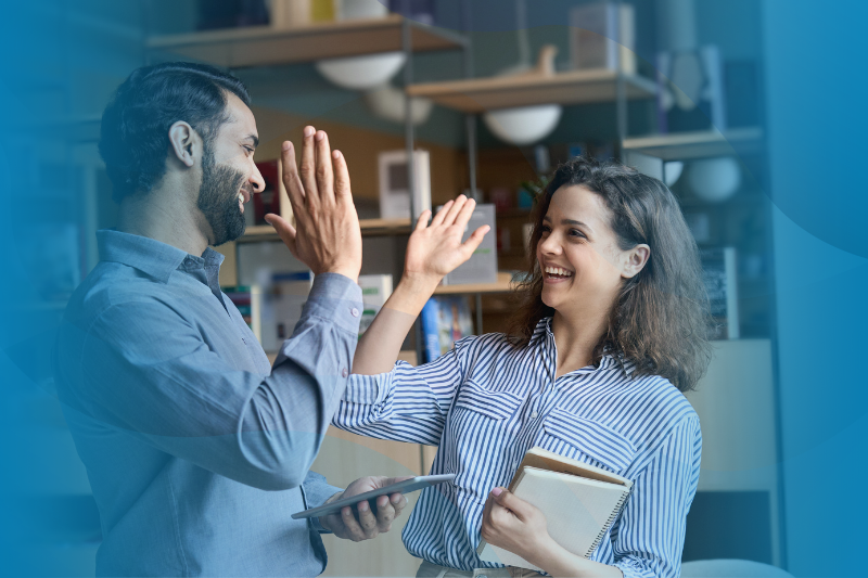 Manager and College Intern Giving High Five Standing in Office Celebrating Success