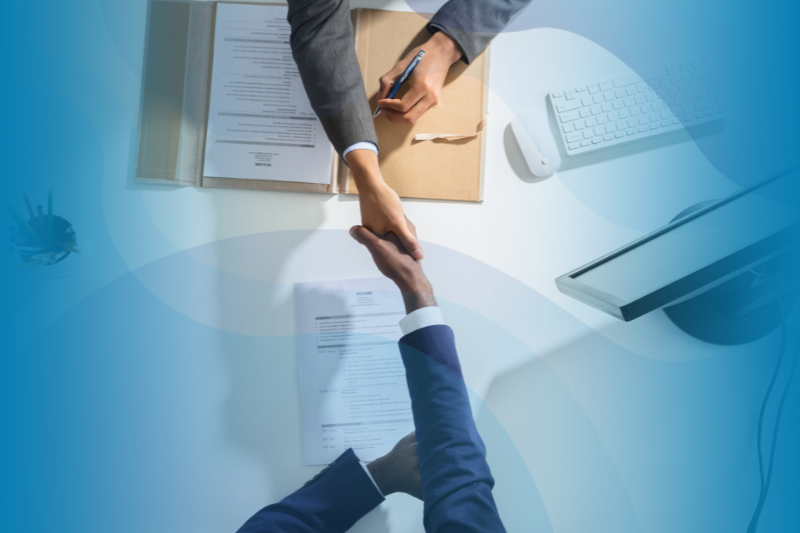 Aerial Shot Of Two People Shaking Hands Over A Desk