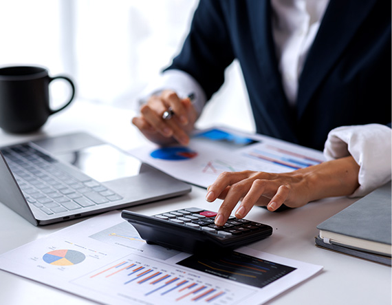 A lady looking at payroll solutions for contingent workers on a computer while using a calculator 