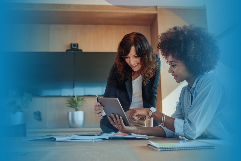 Two women discussing data points on a tablet in an office