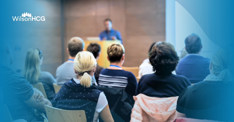 Healthcare conference with attendees facing the stage and speaker at podium