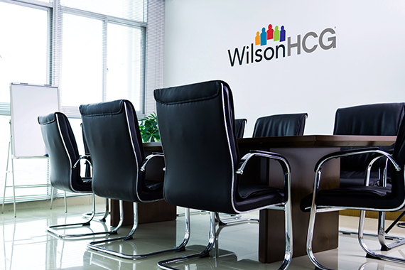 A WilsonHCG office conference table and chairs by a large window and whiteboard