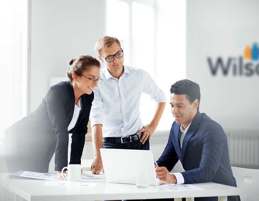 Three WilsonHCG employees collaborating at a desk