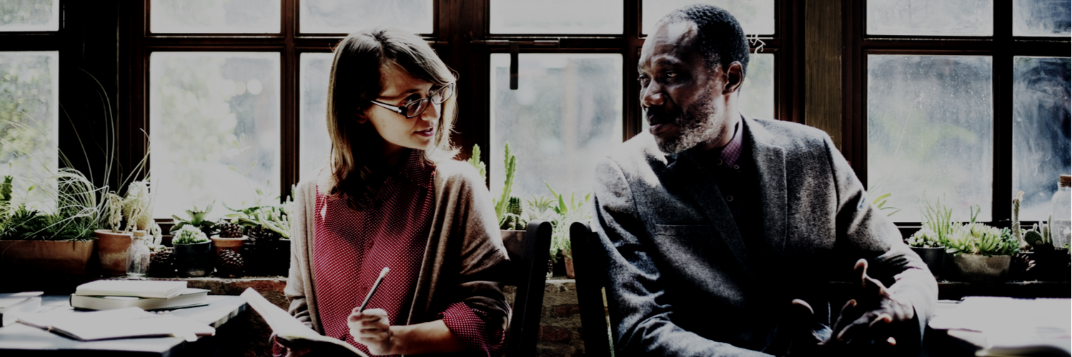 young woman with glasses talking to older coworker